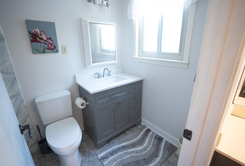 Bathroom featuring a gray vanity with a white countertop and integrated sink, a white toilet, and light-toned flooring