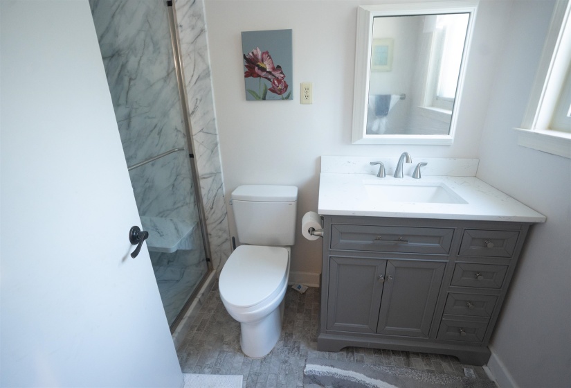 Bathroom featuring a glass-enclosed shower with marble-finish wall panels and a built-in bench
