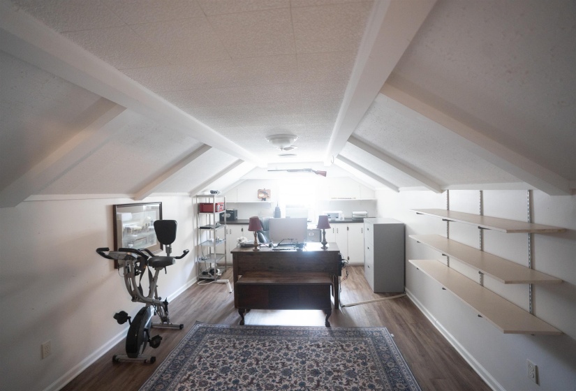 Vaulted ceiling with exposed beams, wood-finish flooring, recessed lighting, built-in shelving, and white baseboards