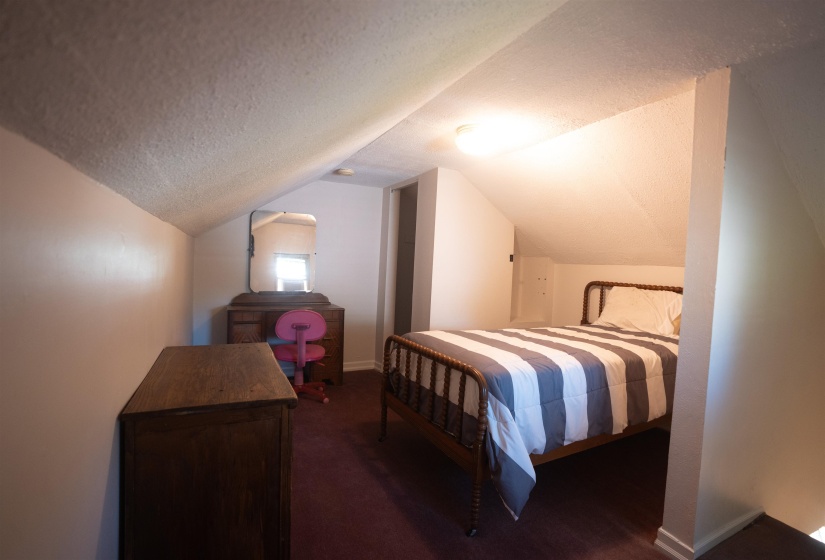 Room with sloped ceilings and recessed wall storage