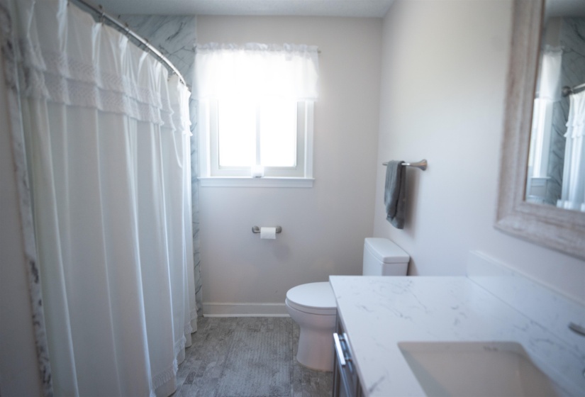 Bathroom featuring a white sink basin, a light-toned countertop, and wood-finish flooring