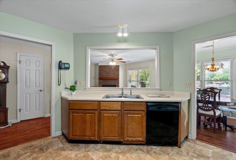 Kitchen featuring a double basin stainless steel sink, black dishwasher, and wood-finish cabinetry