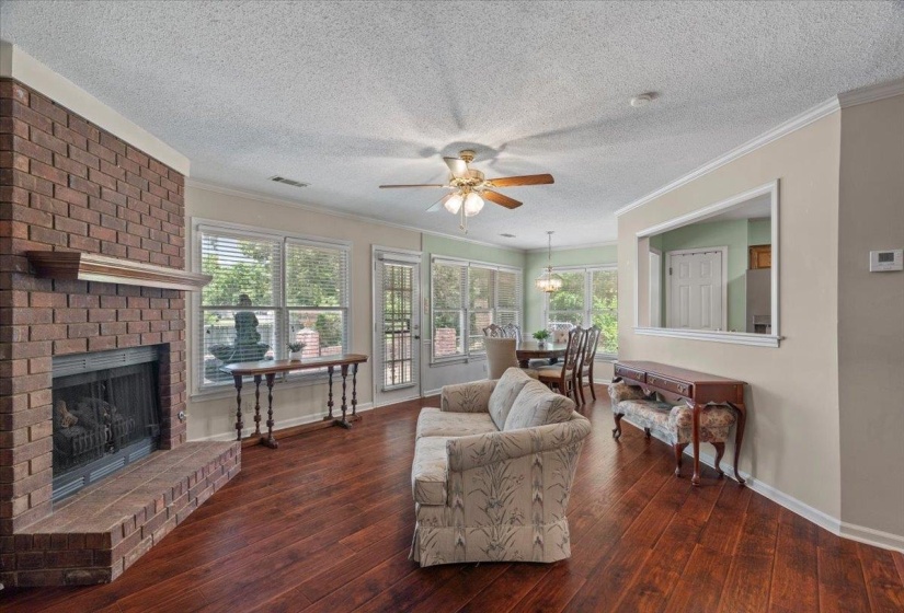 Living area featuring a brick fireplace with a hearth, wood-finish flooring, and crown molding