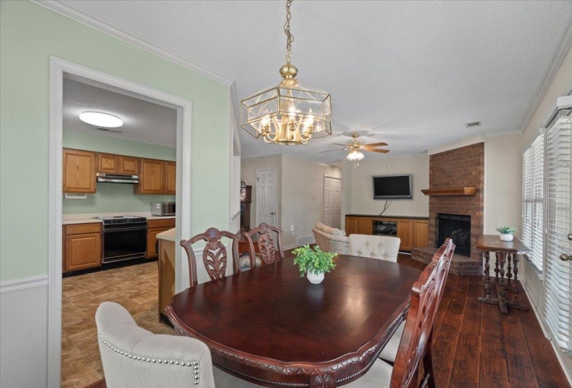 Dining area with wood-finish flooring, a brass-finish chandelier, and crown molding