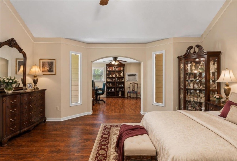 Spacious interior featuring wood-finish flooring, a tray ceiling, and an arched doorway leading to an additional area