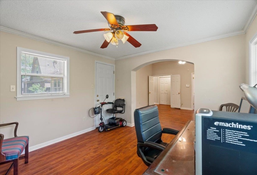 Room with wood-finish flooring, a ceiling fan with light fixture, and crown molding