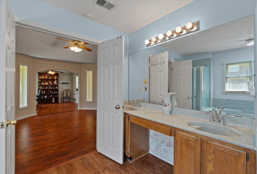 Bathroom vanity featuring dual sinks, a large mirror, and overhead strip lighting