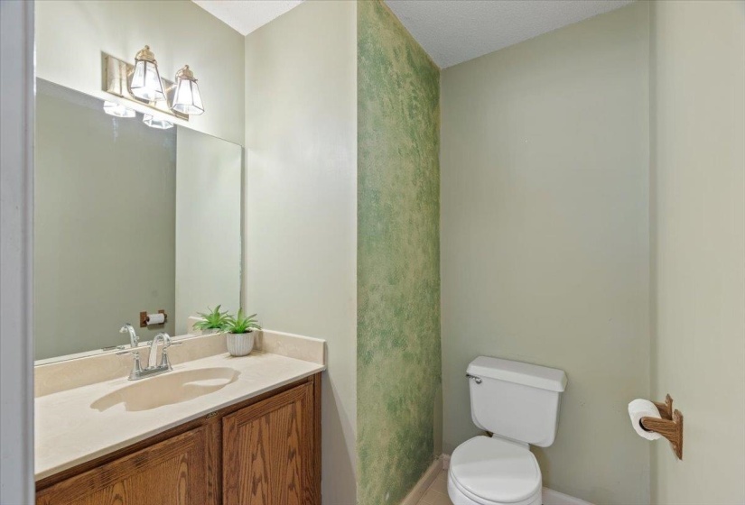 Bathroom vanity with a light-toned countertop, wood-finish cabinetry, and a chrome faucet