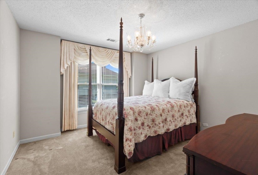 Neutral-toned room featuring a crystal chandelier and large window with blinds and valance