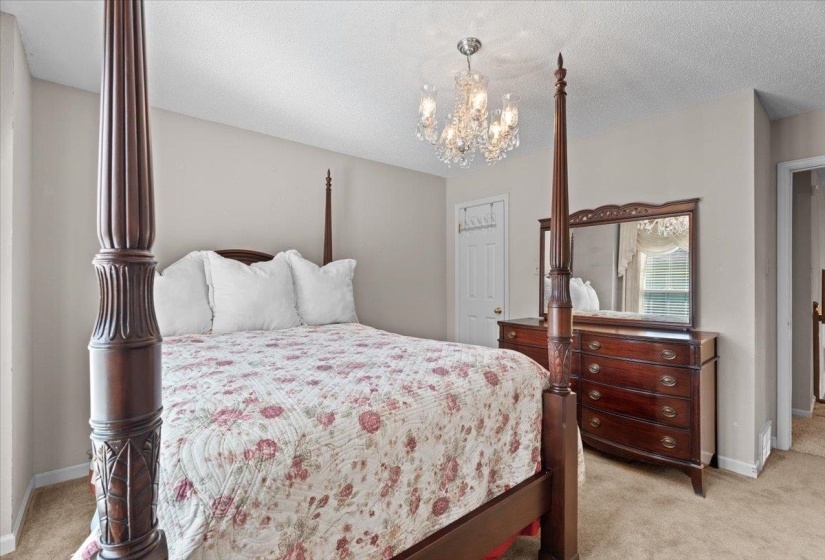 Recessed ceiling with an ornate crystal chandelier, soft neutral wall tones, and carpeted flooring