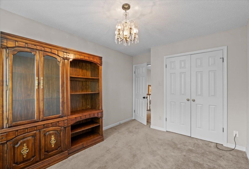 Room featuring a built-in wood cabinet with glass-fronted doors and open shelving, recessed lighting, and a crystal chandelier