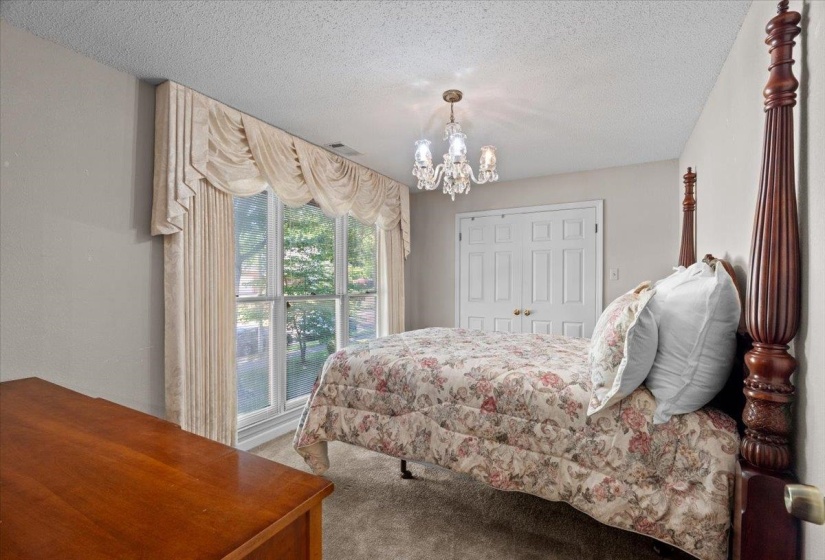 Window with drapery treatments, a crystal chandelier, and bi-fold closet doors