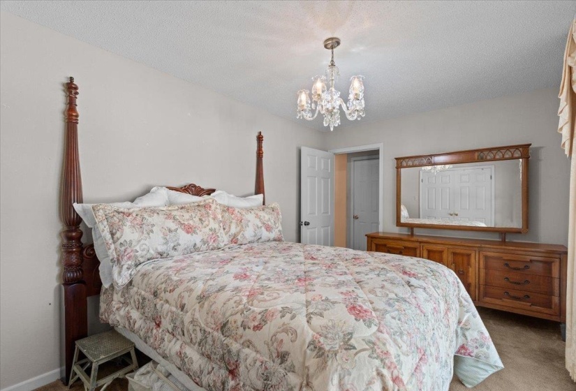 Bedroom featuring a crystal chandelier, neutral wall paint, and textured carpeting