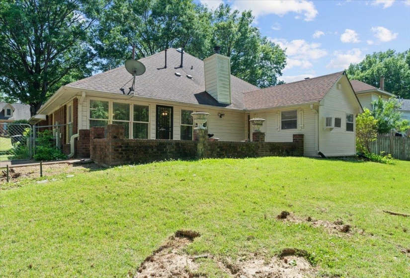 Expansive rear yard featuring a partial brick perimeter wall and a white wood fence