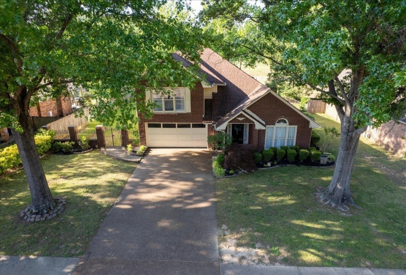 Brick exterior with a peaked roofline, featuring an attached two-car garage and a paved driveway