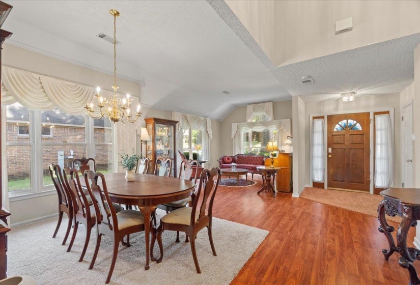 Open-concept interior featuring wood-finish flooring, vaulted ceilings, and large windows