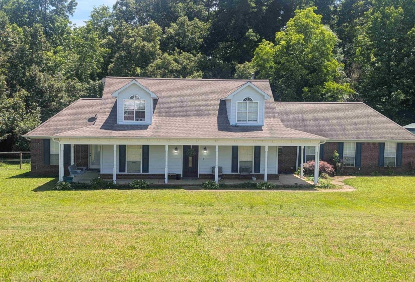 Brick and siding exterior featuring a covered porch with white columns and dormer windows