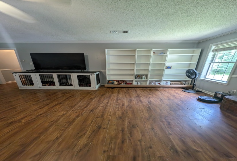 Spacious living area featuring wood-finish flooring, light gray wall paint, and white crown molding