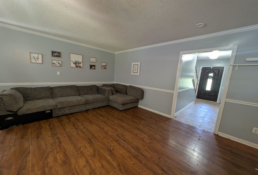 Living area featuring wood-finish flooring, light blue and white two-tone walls, white crown molding, and a recessed ceiling light