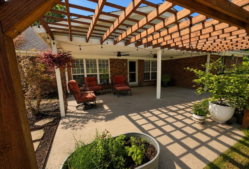 Outdoor patio featuring a wooden pergola, string lighting, and a ceiling fan