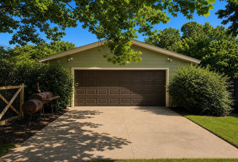 Detached two-car garage with a brown panel door, light green siding, and a concrete driveway, Shop.
