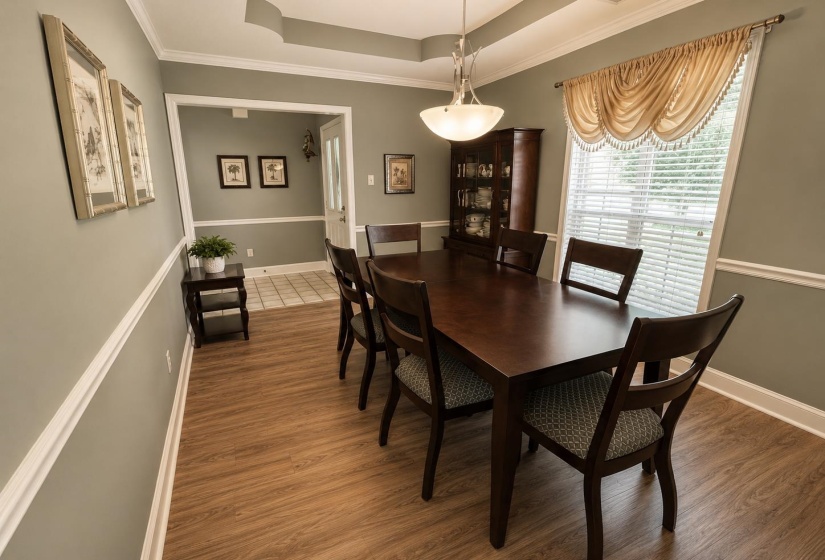 Dining area featuring wood-finish flooring, a tray ceiling, and a large window with blinds