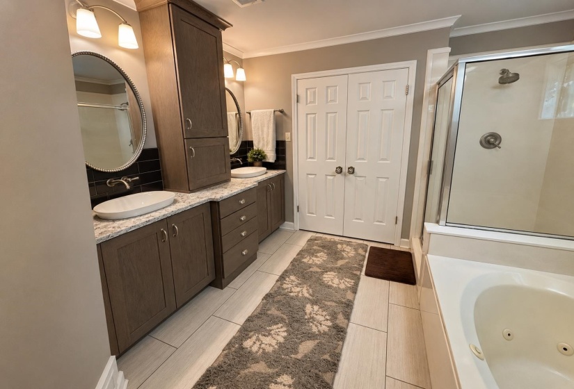 Bathroom featuring dual vessel sinks with wall-mounted faucets, granite-style countertops, and dark cabinetry