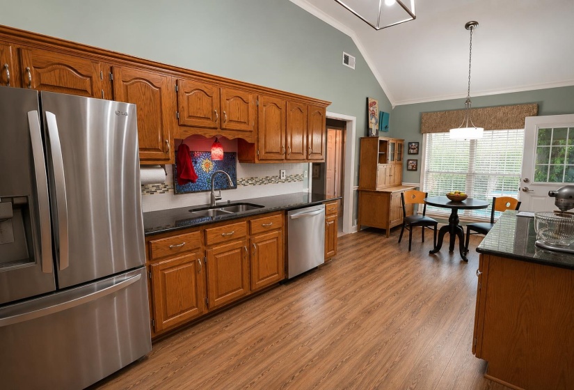 Kitchen featuring wood-finish flooring, vaulted ceiling, and light green wall tones