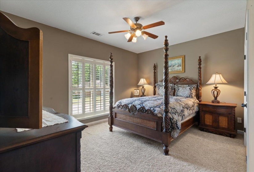 Carpeted room featuring a wide window with white plantation shutters, a ceiling fan with integrated lighting, and neutral wall tones