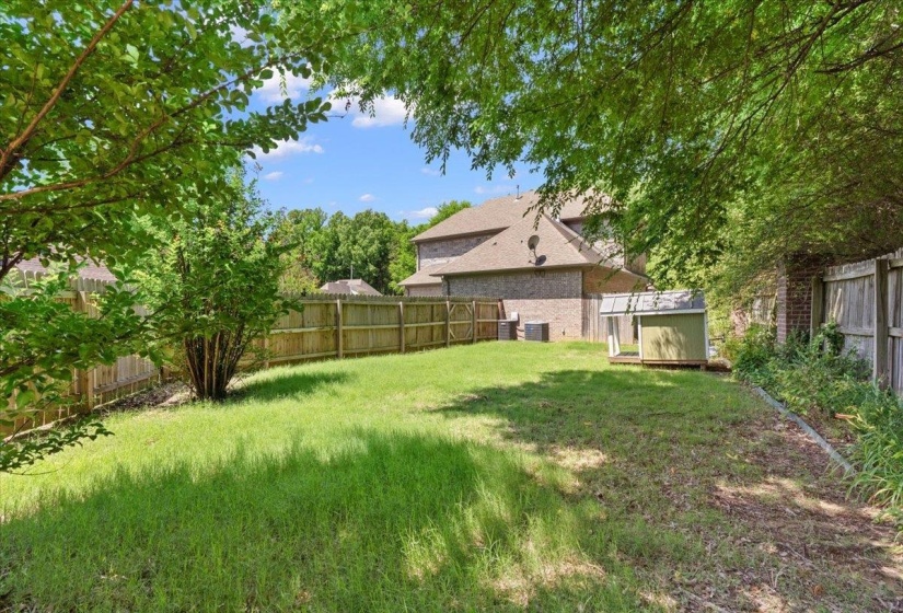 Expansive green lawn with mature perimeter trees and privacy fencing