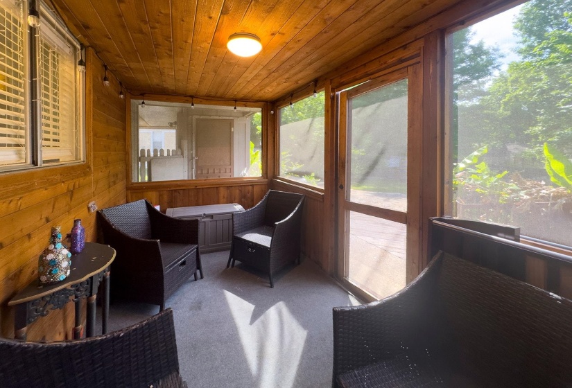 Screened porch featuring wood plank walls and ceiling, a built-in overhead light fixture, and a screened door