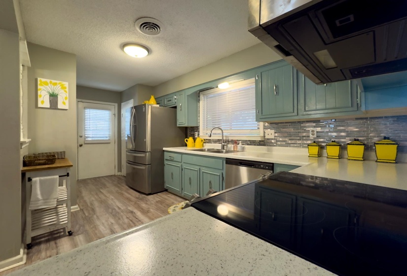 Kitchen featuring light green cabinetry, stainless steel appliances, and wood-finish flooring