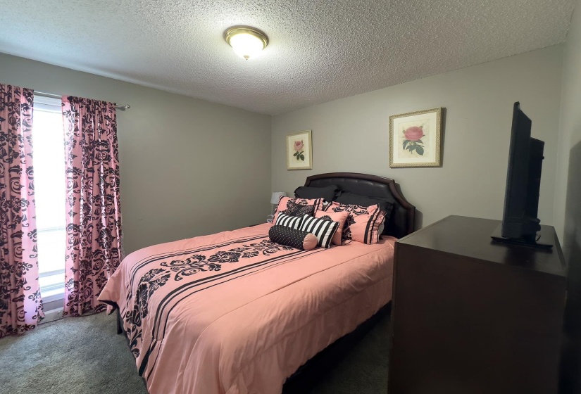 Carpeted room with a window featuring full-length curtains, a ceiling-mounted light fixture, and neutral painted walls