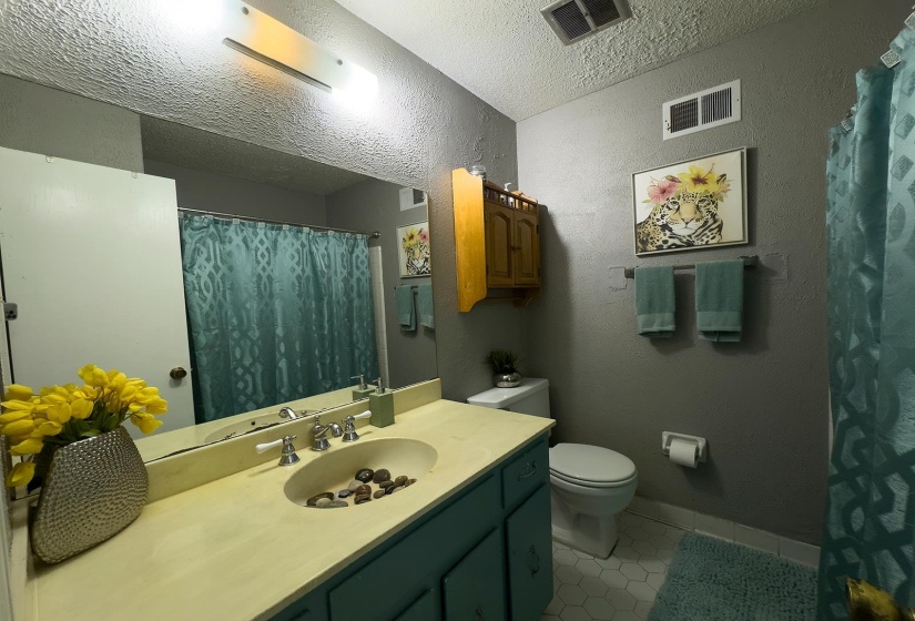 Bathroom featuring a single vanity with an integrated sink, dual-handle faucet, and wood-finish cabinetry