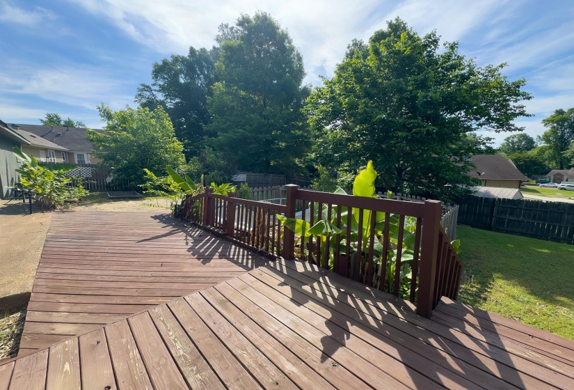 Expansive wood deck with railing, featuring a multi-level design and direct access to a grassy yard
