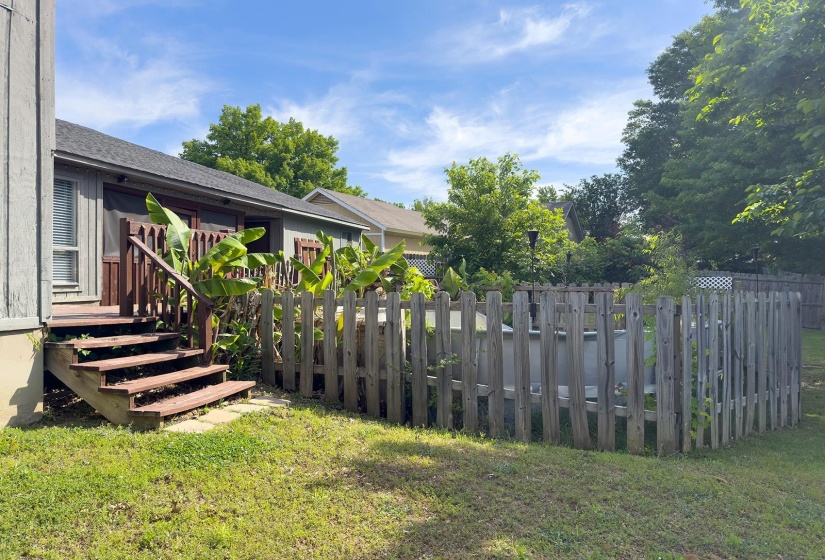 Backyard featuring a wooden privacy fence, a wooden deck with stairs, and established landscaping