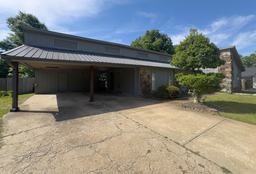 Contemporary exterior featuring a metal roof, stone accents, and a covered carport