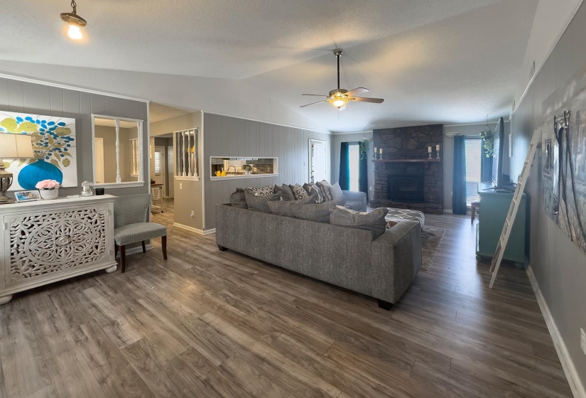 Spacious living area featuring wood-finish flooring, vaulted ceilings, and a ceiling fan