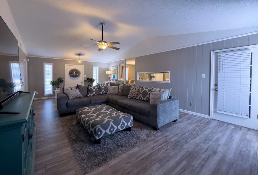 Vaulted ceiling with a ceiling fan, wood-finish flooring, and vertical paneling
