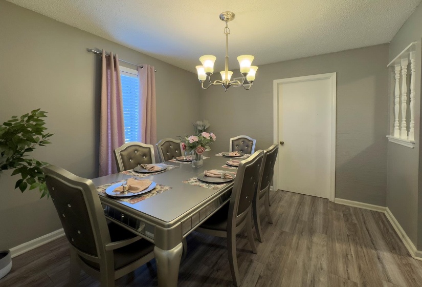 Dining area featuring wood-finish flooring, a contemporary chandelier, and a window with natural light
