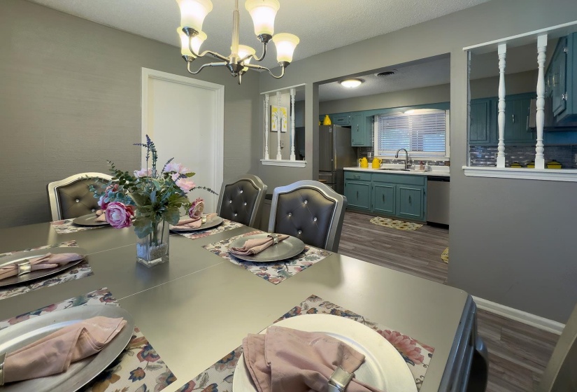 Dining area featuring a chandelier with frosted glass shades and a kitchen with teal cabinetry