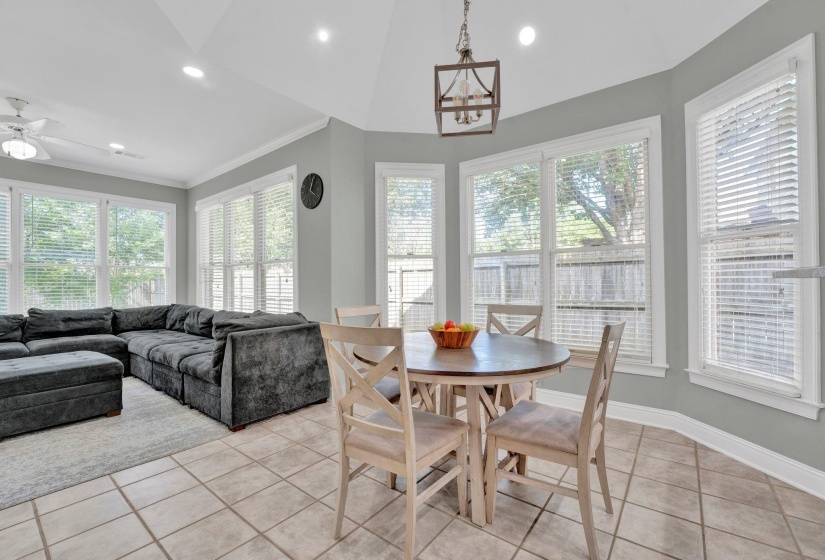 Tiled dining space featuring ceiling fan, vaulted ceiling, and crown molding