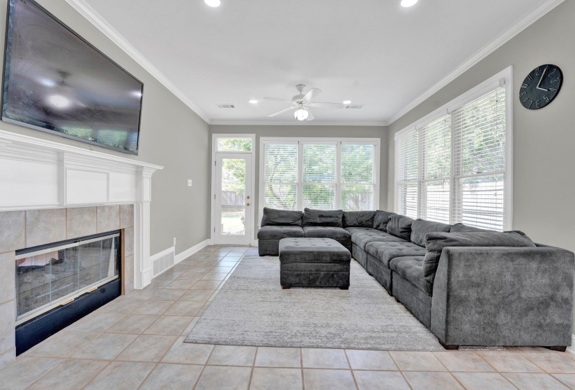 Tiled living room featuring a tiled fireplace, ceiling fan, and ornamental molding