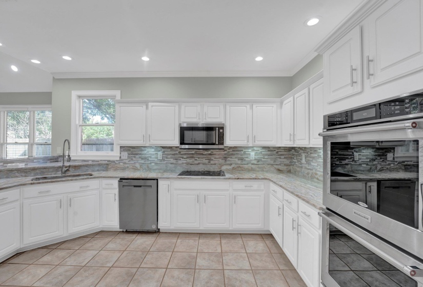 Kitchen with appliances with stainless steel finishes, white cabinetry, decorative backsplash, and sink