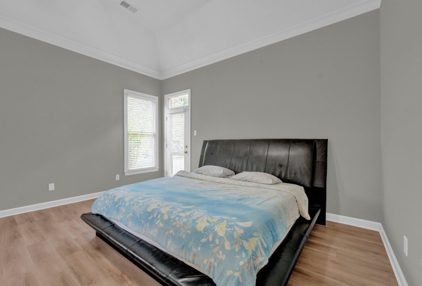 Bedroom featuring vaulted ceiling, crown molding, and hardwood / wood-style floors