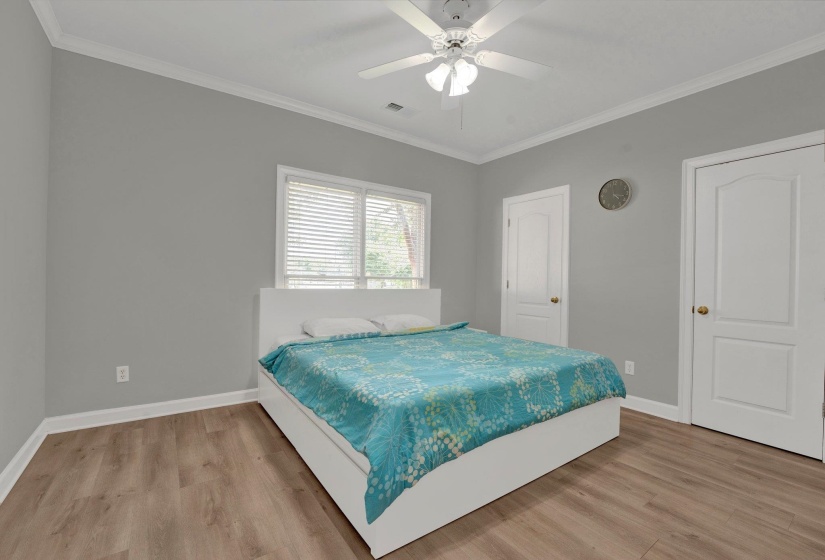 Bedroom with hardwood / wood-style flooring, ornamental molding, and ceiling fan