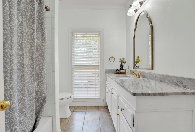 Full bathroom featuring toilet, vanity, shower / tub combo with curtain, tile patterned floors, and ornamental molding