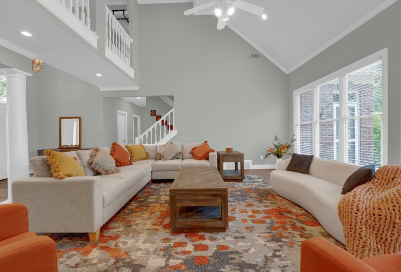 Living room with dark hardwood / wood-style flooring, a wealth of natural light, ceiling fan, and high vaulted ceiling