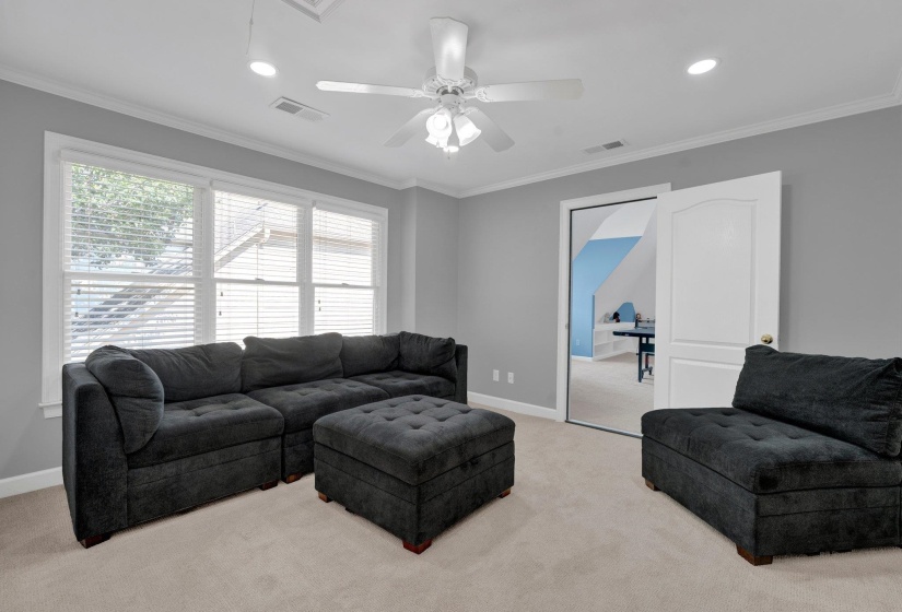 Living room featuring ornamental molding, light carpet, and ceiling fan