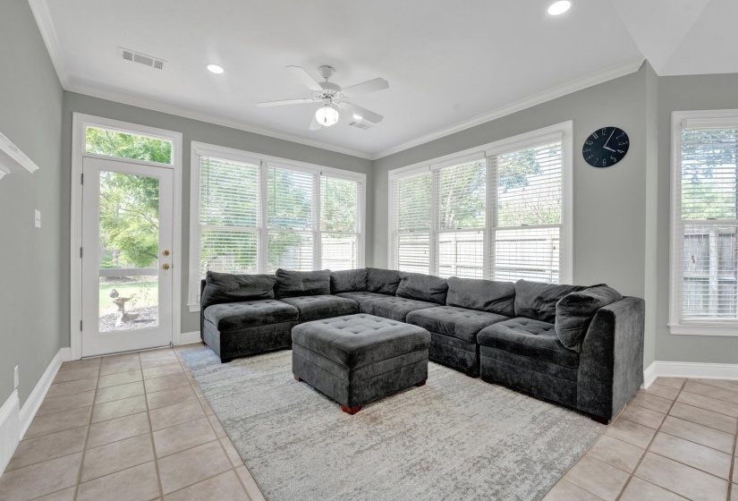 Living room featuring crown molding, ceiling fan, and light tile patterned floors